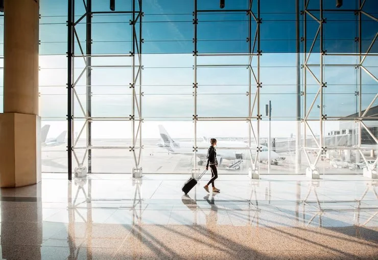 1 view-aiport-window-with-woman-walking-with-suitcase-departure-hall-airport-wide-angle-view-with-copy-space_506452-7790