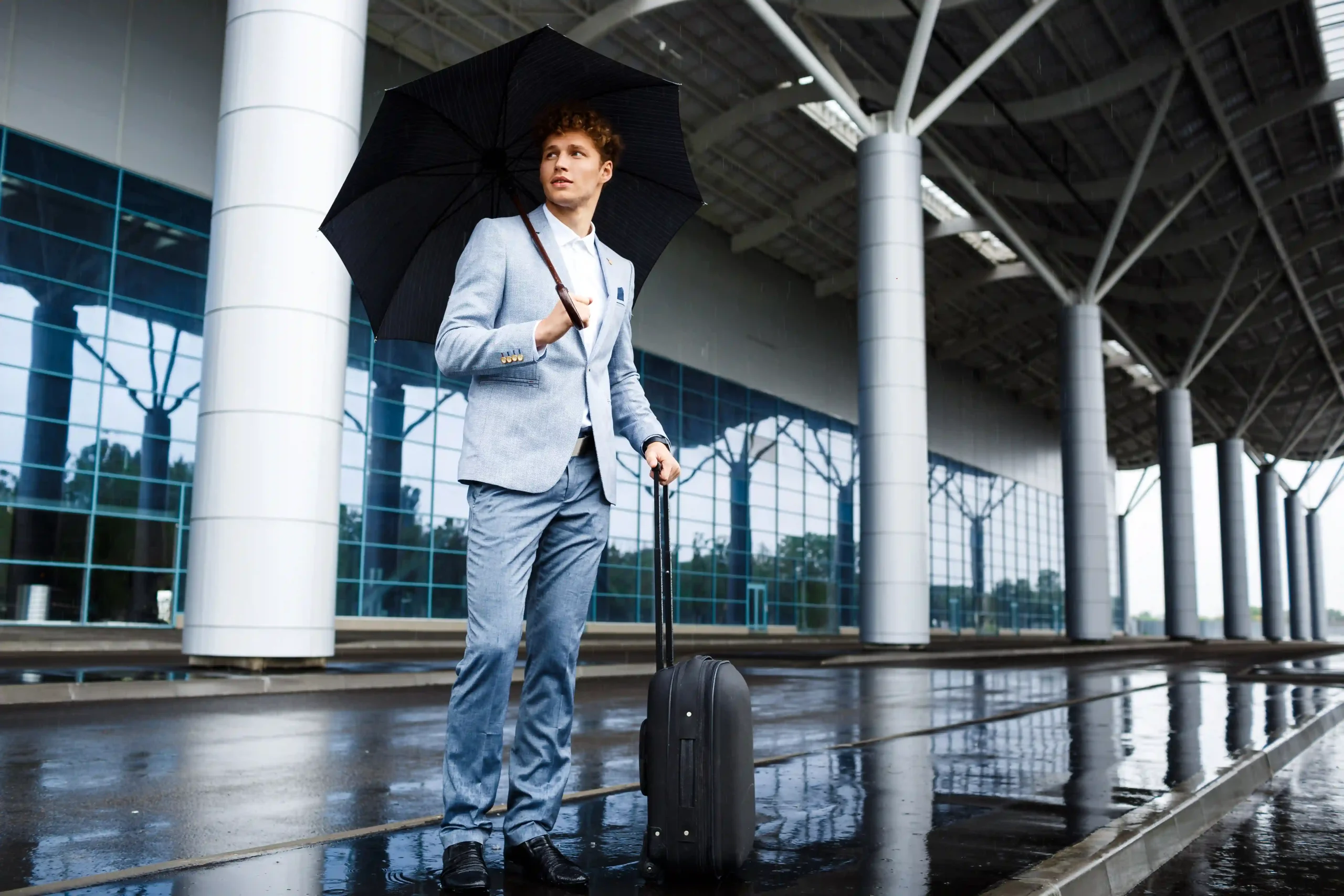 1.picture-young-redhaired-businessman-holding-black-umbrella-suitcase-rain-airport